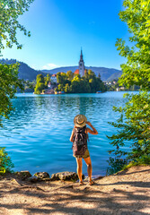 Tourist admiring lake bled island with pilgrimage church of the assumption of maria in slovenia