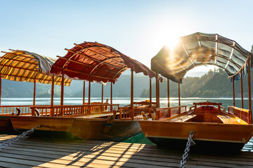 Traditional pletna boats waiting on lake bled at sunrise