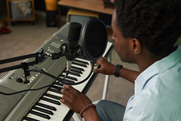 African American singer singing in microphone and recording song in studio