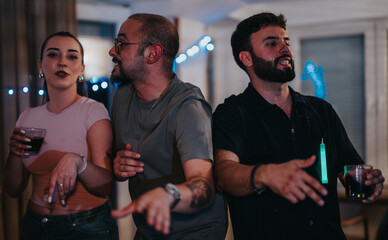 Three friends celebrate a lively indoor birthday party with music and drinks, showcasing joy and camaraderie in a festive atmosphere with string lights.
