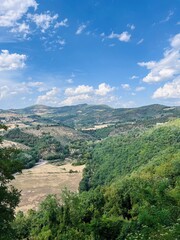 Obraz premium Beautiful hillside landscape under a bright blue sky with fluffy clouds. Assisi, Italy.