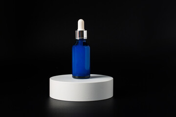 Blue glass cosmetic bottle, Skin care or sunscreen cosmetic with stylish props on black background.