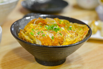Japanese food concept. Chicken and egg rice bowl or Oyakodon in a black bowl with green onion topping.