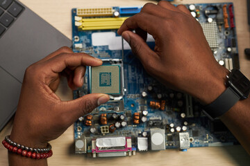 Close-up of repairman setting chip in motherboard of computer in workshop