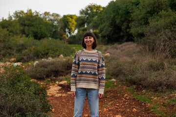 Active lifestyle..Young happy female tourist looks around, relaxes in nature while hiking in the forest.