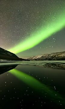 Experience the beauty of the northern lights illuminating a serene lake under a starry sky
