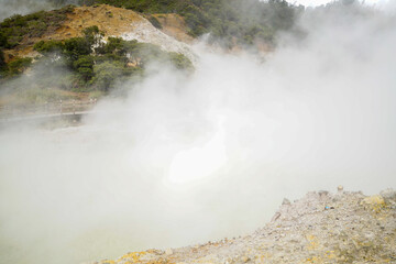 A misty, foggy mountain range with a large body of water in the foreground