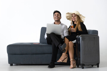 Relaxed happy couple sitting and planning vacations trip on couch over white background. Summer vacation concept.