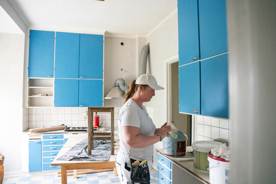 Side view of female painter wearing gloves at workplace