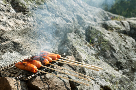 Close-up of sausage skewers getting grilled on campfire