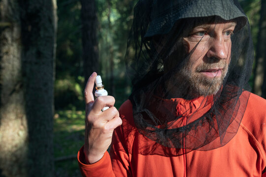 Close-up of man holding repellent spray while wearing insect proof hat