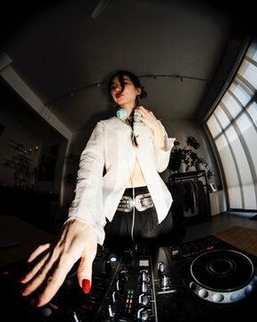 close-up perspective of a DJ's hands adjusting knobs and sliders on a professional DJ mixer with vibrant lighting, capturing the focus and precision of the performance.