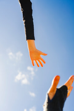Close-up of father and son reaching hands against sky