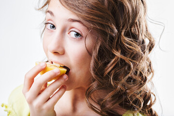 Cute girl biting into a slice of lemon with a funny expression