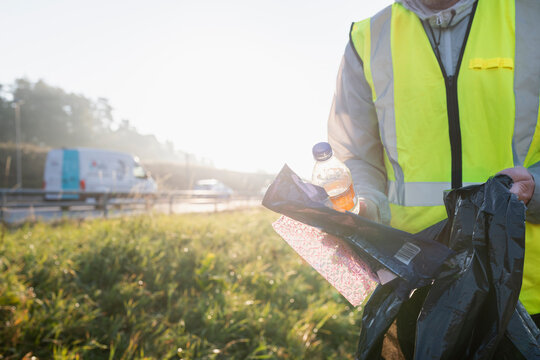 Midsection of male sanitation worker collecting garbage at sunny day