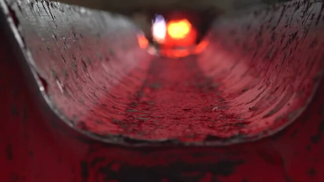 Witness the intense process of hot steel billets being transported on a conveyor in a steel mill. The glowing metal highlights the industrial operation.