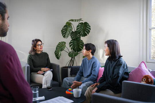 Teenage boy talking with medical professional while sitting with parents in rehabilitation center
