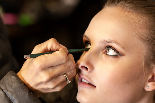 Cropped hand of artist applying kajal eyeliner to fashion model