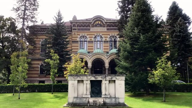 Religious building with trees and grass in the foreground. Holy Synod of the Bulgarian Orthodox Church in Sofia, Bulgaria. 