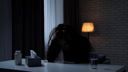 Silhouette of woman suffering mental health issues, sitting at the table in front of camera,...