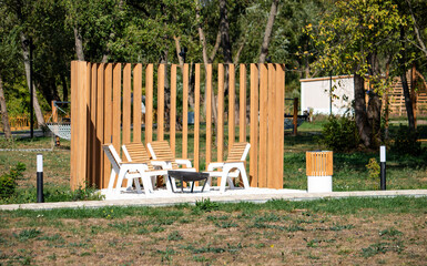 A wooden fence with a bench and chairs in front of it