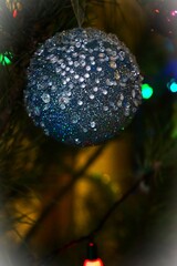 A shiny New Year's ball against the background of a Christmas tree and garlands
