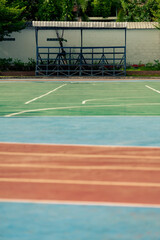 A sports area with multiple colored surfaces, covered seating area with several benches in background