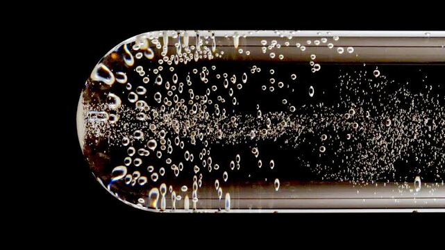 Close up tablet of aspirin, vitamin falls into of water in glass test tube in slow motion on black background. Macro shot of bubbles effervescent. The medicine concept, health care, treatment.FullHD 