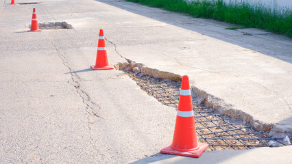 Renovate the old damaged broken road with Reinforcement steel rebar structure and traffic cones on...
