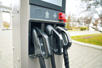 Fototapeta premium EV charger plugs close-up. Electric vehicle charging station with plug-in connectors in city street. Clean energy, renewable power, and sustainability. Selective focus