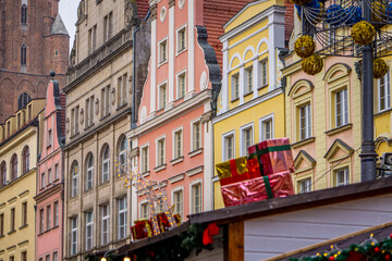 Fototapeta premium stalls at a Christmas and New Year's market in a big city. Christmas tree decorations and decorations, lights, baubles, garlands against the background of urban architecture, old historic tenement hou