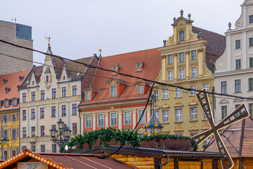 Obraz premium stalls at a Christmas and New Year's market in a big city. Christmas tree decorations and decorations, lights, baubles, garlands against the background of urban architecture, old historic tenement hou