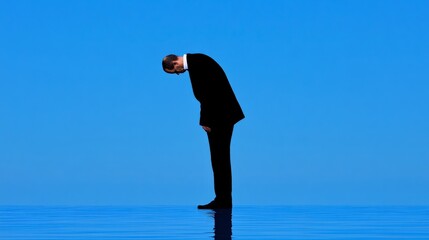 A Man in Deep Thought: A solitary figure in a black suit bends forward in deep contemplation, his silhouette stark against a vibrant blue sky, creating an atmosphere of introspection and uncertainty.