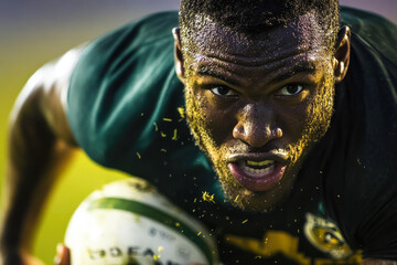 African male rugby player in action with intense expression on field