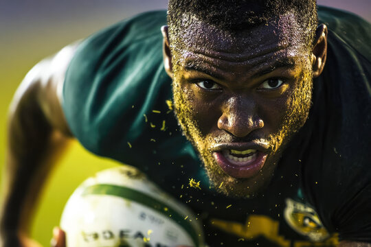 African male rugby player in action with intense expression on field