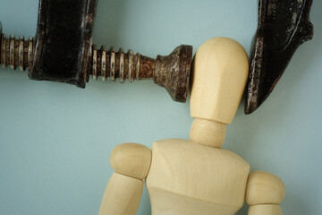 Wooden mannequin squeezed in iron vise tool - Concept of heachache, stress and psychological pressure