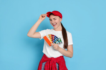 Portrait of young decorator with color palettes on light blue background