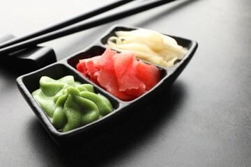 Hot wasabi paste, ginger and chopsticks on grey table, closeup