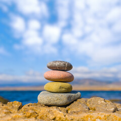 heap of varicoloured sea stones on a coast under blue cloudy sky