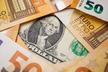 Close up of fifty euro money bills and a dollar bill in the middle background