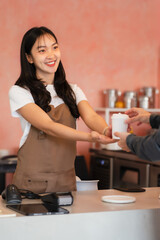Business Owner Concept - Barista offers disposable take away hot coffee at the modern coffee shop.