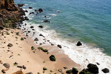 Scenic rocky beach with sunbathers and waves.