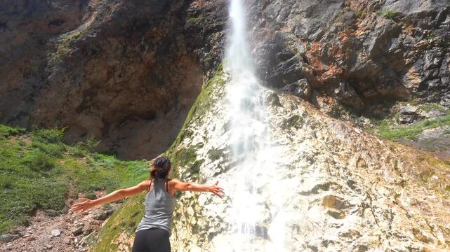 Female hiker enjoying majestic rinka waterfall in picturesque logarska dolina valley, savinja alps, slovenia, during summer