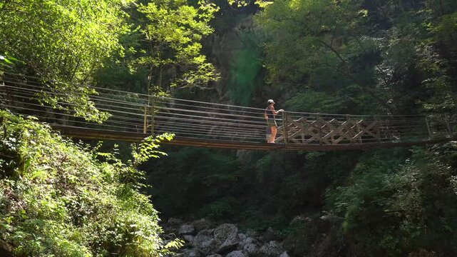 Mother and child walking on a suspended wooden bridge over tolmin gorge in triglav national park, slovenia, during summer holidays