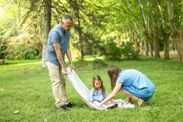 Fototapeta premium Parents wrapping daughter in blanket in park during summer day