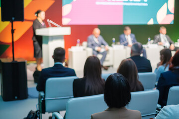 Professional business event featuring speakers on stage, audience seated, sharing ideas and expertise.