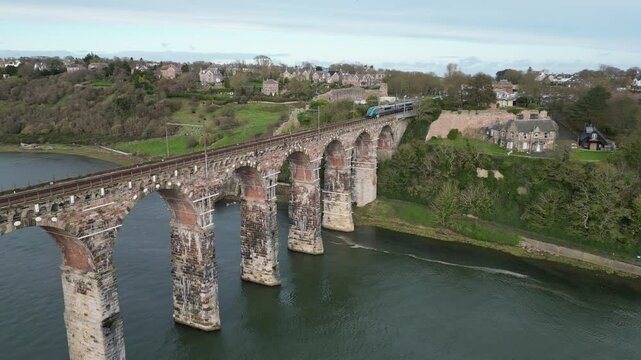 Drone pullback view of a train passing on Royal Border Bridge on River Tweed