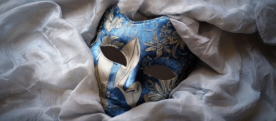 Handcrafted decorative blue fabric mask adorned with intricate symbols displayed on a silver...