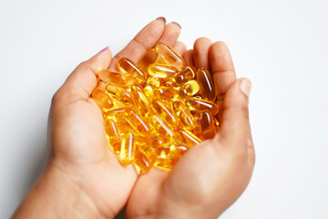 closeup image of hand holding omega 3 capsules on white background