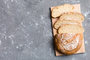 Freshly baked bread slices on cutting board against white wooden background. top view Sliced bread